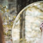 Photo of woman in forest looking into mirror by prinzesskathrin for Pixabay